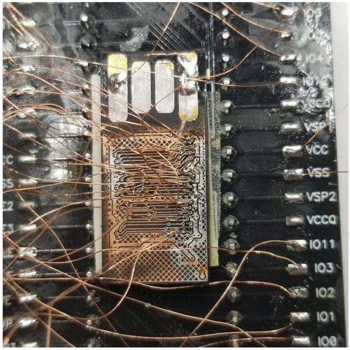 Monolithic memory with its protective layer removed and dozens of copper wires soldered to the test points